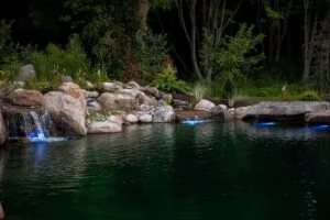 Tranquil pond with illuminated waterfall and rocks