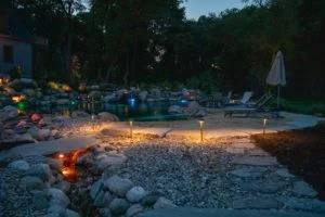 Illuminated backyard patio with pool at dusk.